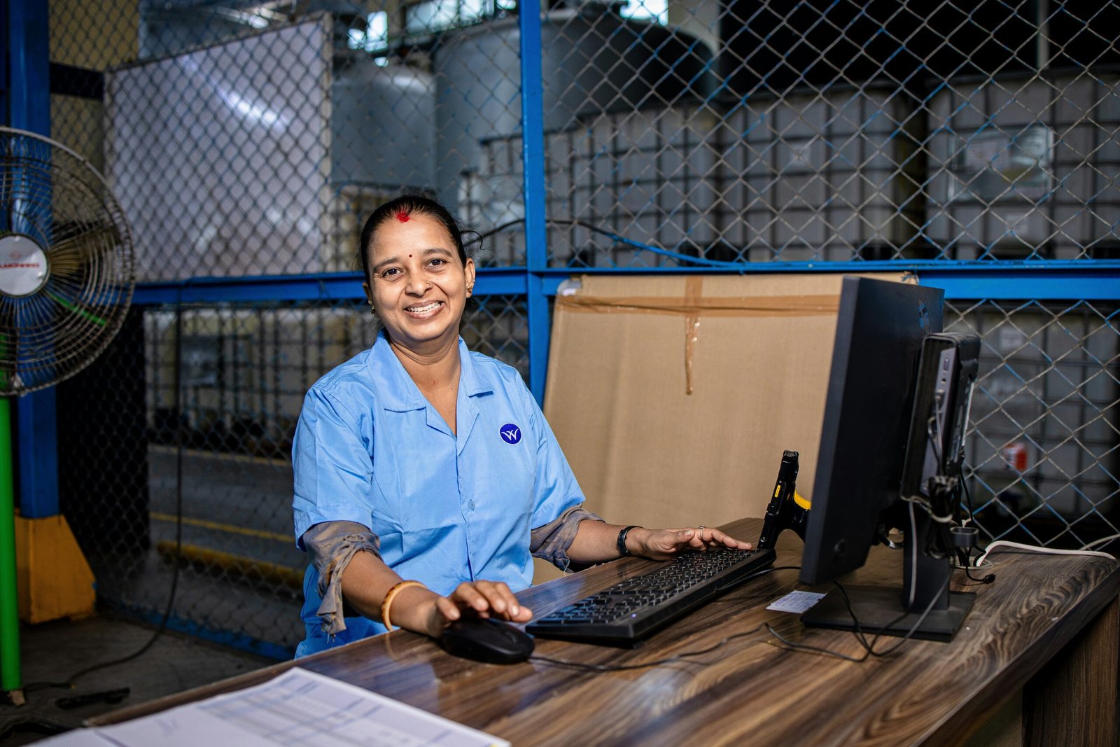 A smiling woman holding her customizable smart clock while working at a desk.