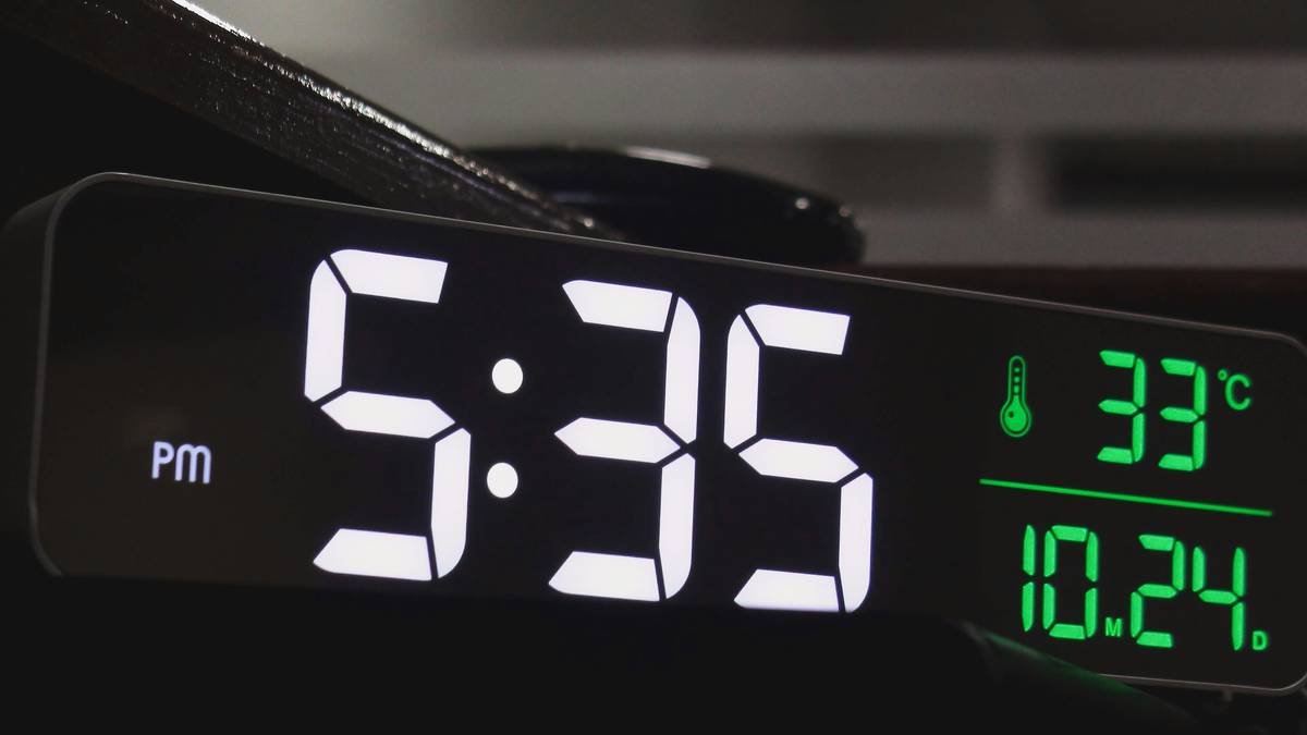 A smart clock synced with orange-toned smart light bulbs creating a relaxing atmosphere