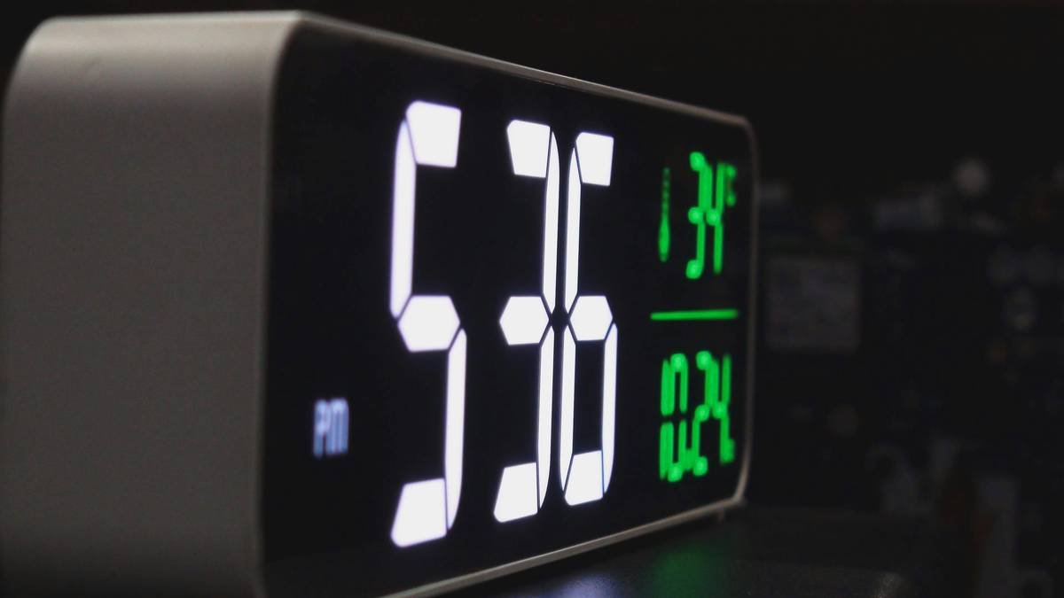 A sleek health stats clock sitting on a nightstand beside plants
