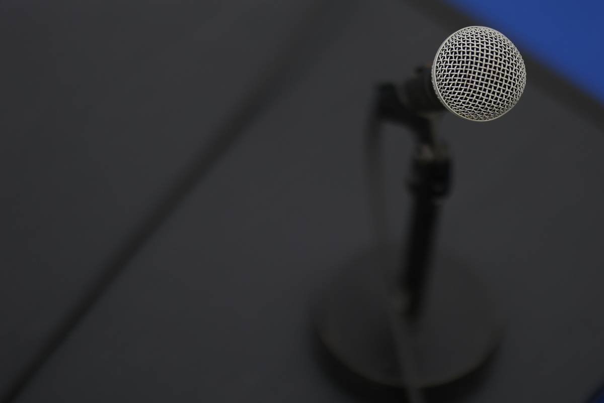 A sleek voice assistant clock placed on a wooden bedside table next to a plant